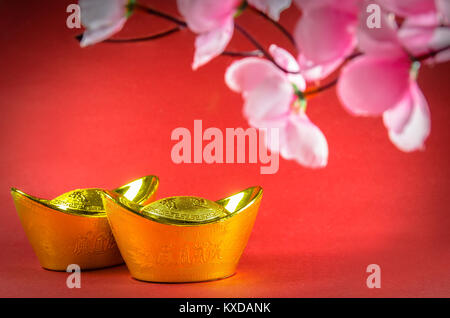 Chinese New Year gold ingots decorations on red background. (English translation for foreign text means blessing). Stock Photo