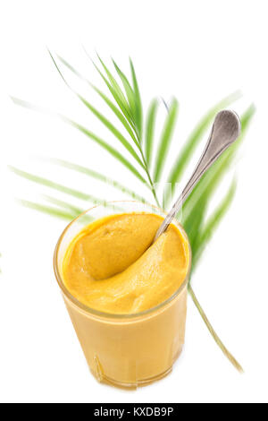Glass jar of mustard isolated on the white background bottom view againt green palm leaf on white Stock Photo
