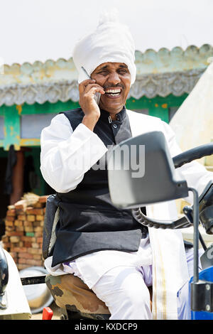 1 Indian Rural Farmer talking Mobile phone while driving Tractor Stock Photo