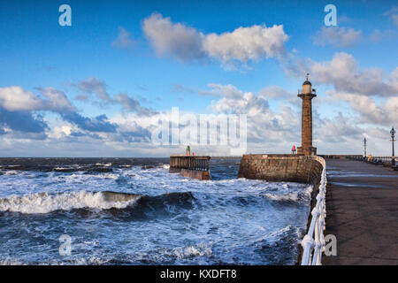 Wind and a rising tide produce rough seas at the entrance to Whitby Harbour in North Yorkshire, on a bright winter afternoon. Stock Photo