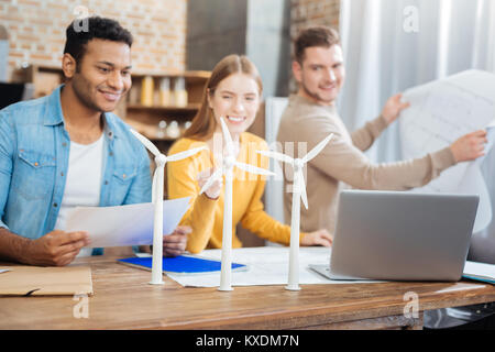 Positive eco engineers smiling while looking at the windmill turbines Stock Photo