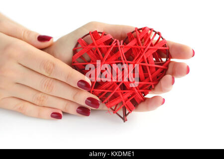 Wicker red heart in woman's hands on white background. Closeup heart in hand of girl with red manicure. Happy Valentines day, love concept. Stock Photo
