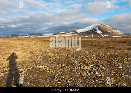 Shadow of a human, polygonal structural soil on the Platåberget, snow-covered peak Nordenskjöldfjellet in the back Stock Photo