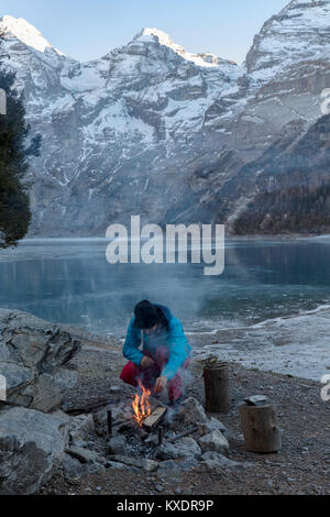 Campfire on Lake Oeschinen, behind it Blüemlisalphorn, Bernese Oberland, Switzerland Stock Photo