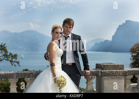 Young bride and groom posing on shore promenade in front of sea panorama