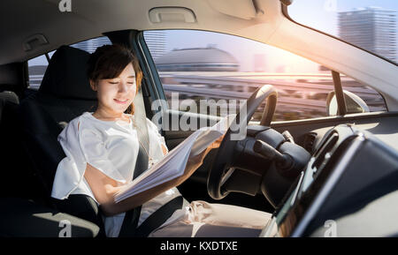 young woman reading a book in a autonomous car. driverless car. self driving vehicle. heads up display. automotive technology. Stock Photo