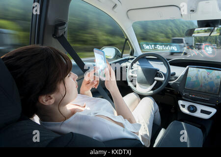 woman using smart phone in autonomous car. self driving vehicle. driverless car. autopilot. automotive technology. Stock Photo