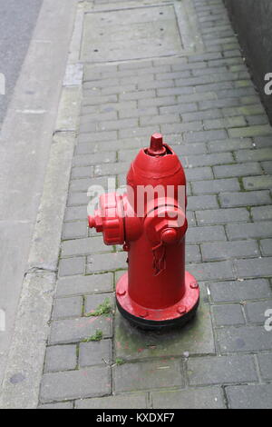 Red fire hydrant on stone paved sidewalk, urban street Stock Photo