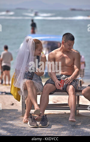 Newly married couple on honeymoon with the bride seemingly reluctant to let go of her big day. . Thailand Southeast Asia Stock Photo