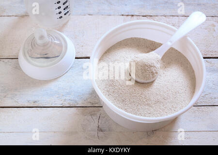 Powdered infant formula in a spoon while preparing child food mash next to a baby bottle. Empty copy space for Editor's text. Stock Photo