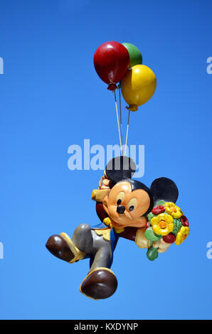 Monchique, Faro - Portugal, 30th, March 2013. Studio image of Mickey Mouse figure hanging from three balloons with a blue sky background. Stock Photo