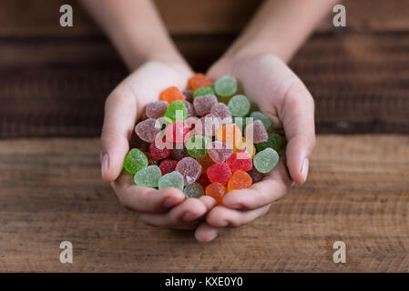 hand showing pile of gumdrop on a wooden table background Stock Photo