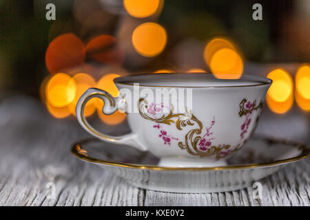 Empty Cup On Saucer on a wooden table with electric garland in bokeh with lights in defocused background Stock Photo