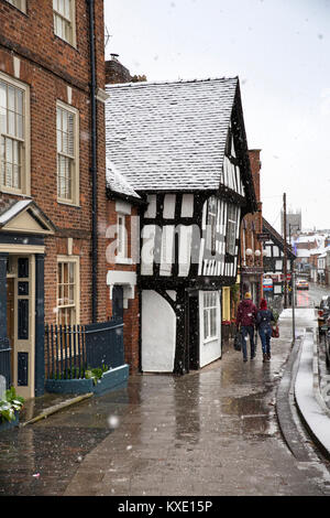 UK, England, Cheshire, Nantwich, Welsh Row, couple walking past old half timbered house in winter snow Stock Photo