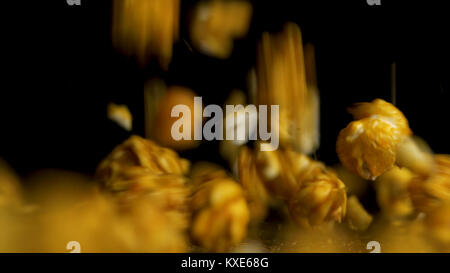 Falling pop corn on black background. Popcorn falls isolted on black background. Pouring popcorn on dark background Stock Photo