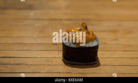 Close up of chopsticks taking portion of sushi roll on the table restaurant, eating sushi roll using chopsticks. Sushi roll on wooden background Stock Photo