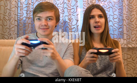 Couple playing video games. Young couple playing video games in their apartment. Young couple playing video games in the living room. Competitive couple playing video games Stock Photo