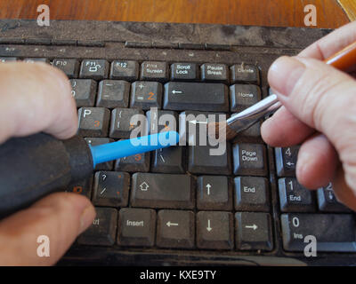 Cleaning dirty dusty computer keyboard by hand air blower and brush Stock Photo