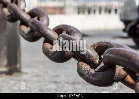 Close up view of rusty metal chain links on a blurred square at background Stock Photo