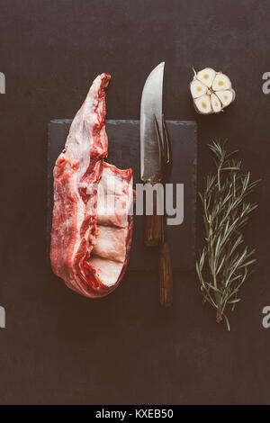 top view of raw pork ribs on stone slate with cutlery and spices Stock Photo