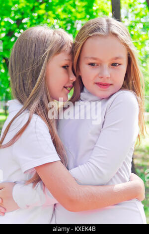 Photo of two smiling whispering girls in summer Stock Photo