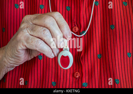 Close up of hand holding life-saving personal alarm for the elderly and disabled people showing pendant with push button Stock Photo