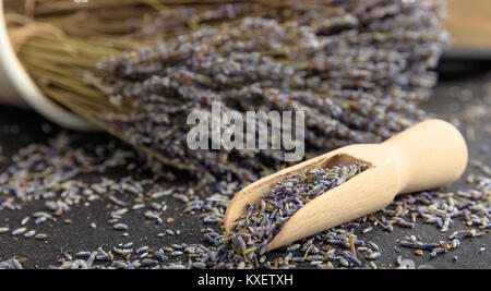 Dried lavender bunch and wooden scoop on black background Stock Photo