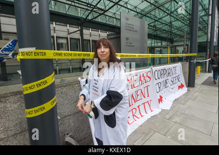 A protester in a cow costume puts up tape with the message 'Crime Scene Do Not Enter' across the front of the Dept fo Busines Innovations & Skills. TTIp is a secret trade deal  which gives corporate profits priority over democratic governments. Stock Photo