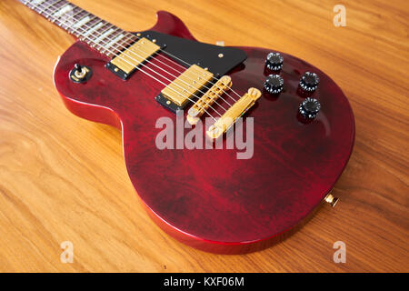 Shiny Wine Red Guitar With Golden Hardware on A Wooden Table Side View Stock Photo