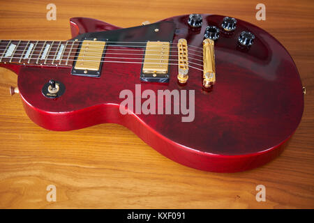 Shiny Wine Red Guitar With Golden Hardware on A Wooden Table With Focus on the Pickups Stock Photo