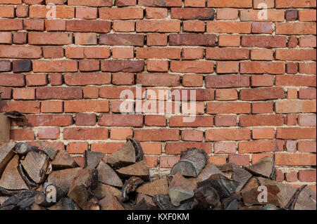 Background of old vintage brick wall with pile of firewood at the bottom Stock Photo