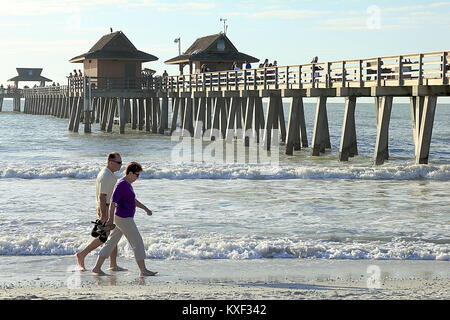MIAMI, FLORIDA - NOVEMBER 28, 2013: Happy senior couple enjoys a romantic stroll on the beach near the pier Stock Photo