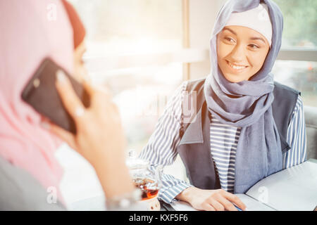 Muslim Woman On Break Using Mobile Phone In cafe Stock Photo