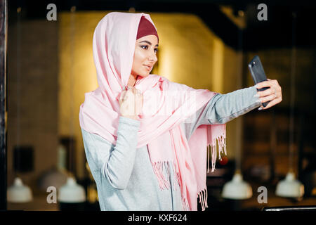 Arabian muslim woman taking selfie with phone in cafe Stock Photo