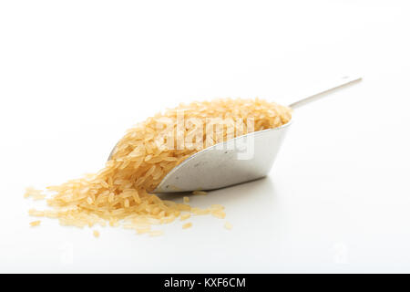 Raw parboiled rice in a metallic scoop on white background Stock Photo