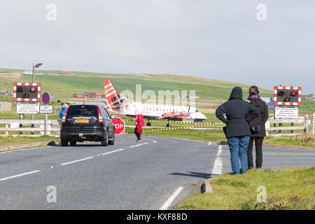 Sumburgh Airport, Shetland Islands, Scotland, UK - road crossing closed to allow Loganair flight to land, watched by tourists Stock Photo