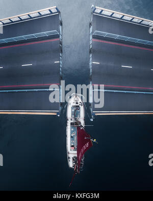 Looking down from the top of Tower Bridge, London while a sailing barge cruises beneath the lifted bridge gates. Stock Photo