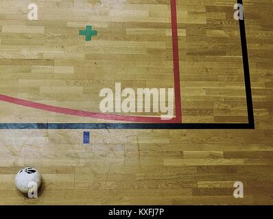 Red and black line marks and football balll on hardwood sporting floor.  Worn out wooden floor of sports hall with colorful marking lines Stock Photo
