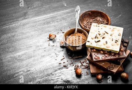 Bars of different types of chocolate with cocoa powder. On the black chalkboard. Stock Photo