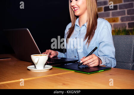 Graphic designer sitting at table in cafe and  using digital tablet and computer tools working on a new project. Stock Photo