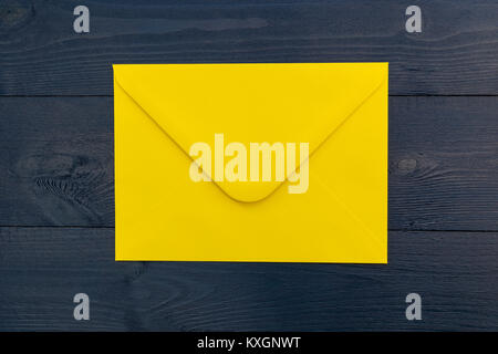 Bright yellow envelope on blue wood table background Stock Photo