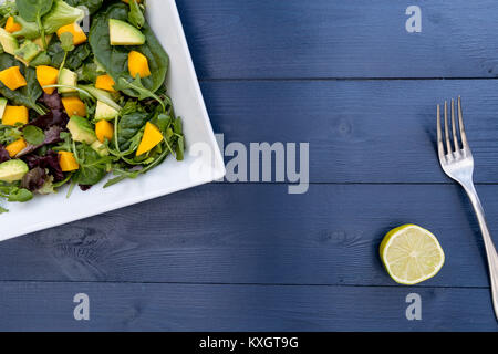 Lunch plate of mango avocado salad on blue wood table background Stock Photo