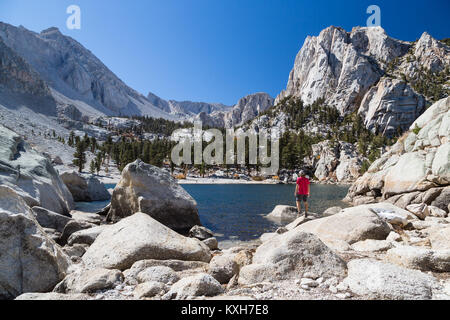 A man admires the view of Lone Pine Lake looking up towards the Sierra Nevada Mountains and the route to Mt. Whitney. Stock Photo