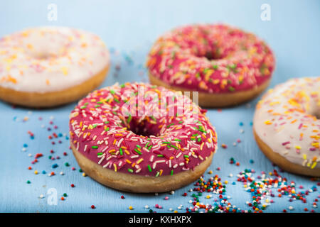 Multicolored donuts close-up on a blue wooden background. Delicious dessert. Stock Photo