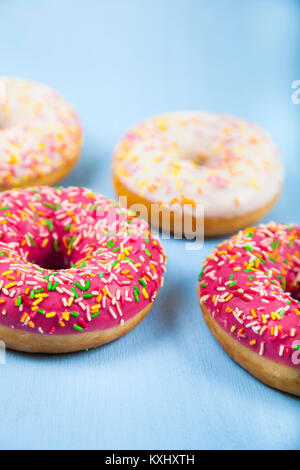 Multicolored donuts close-up on a blue wooden background. Delicious dessert. Stock Photo