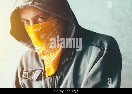 Hooded gang member criminal with scarf over face looking at camera, headshot portrait Stock Photo