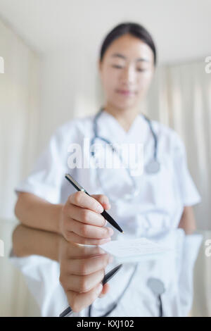 Close-up of female doctor writing prescription at table in clinic Stock Photo