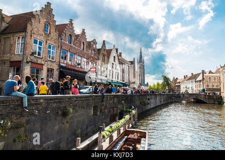 Bruges, Belgium, - August 31, 2017: The Dijver canal and the tower of the Church of Our Lady with people around in the medieval city of Bruges, Belgiu Stock Photo