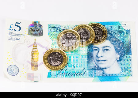New british five pound note with one pound coins, isolated on white background. Stock Photo