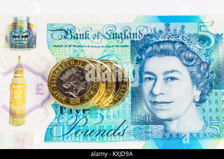 New british five pound note with one pound coins, isolated on white background. Stock Photo